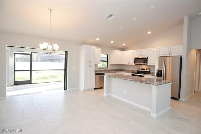 kitchen featuring stainless steel appliances, visible vents, white cabinets, hanging light fixtures, and dark stone counters