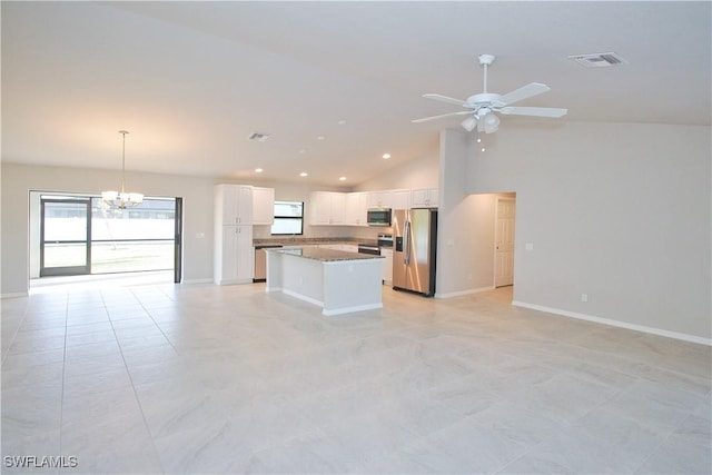 kitchen featuring decorative light fixtures, dark countertops, appliances with stainless steel finishes, white cabinets, and a kitchen island