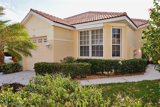 view of side of home featuring a tiled roof, an attached garage, and stucco siding