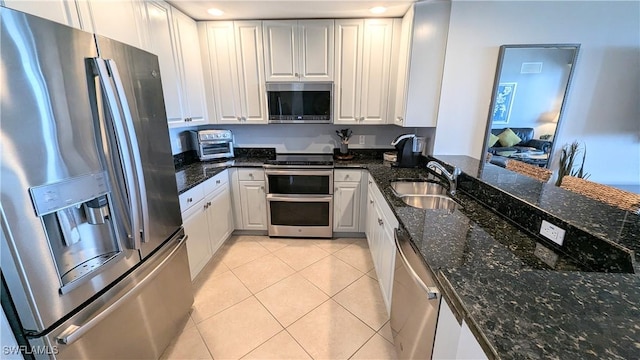 kitchen featuring light tile patterned floors, a toaster, stainless steel appliances, a sink, and white cabinetry