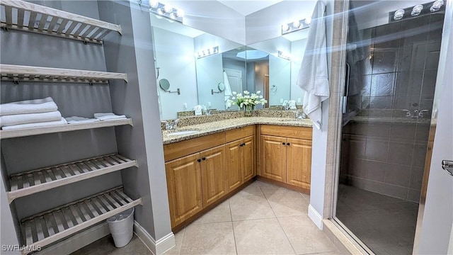 bathroom featuring double vanity, a stall shower, a sink, and tile patterned floors