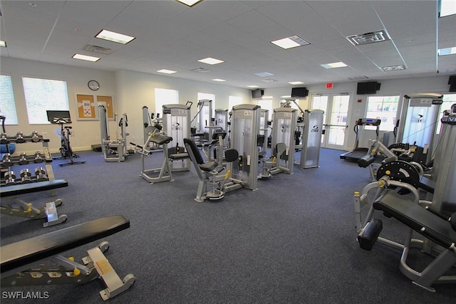 exercise room with baseboards, visible vents, and a drop ceiling