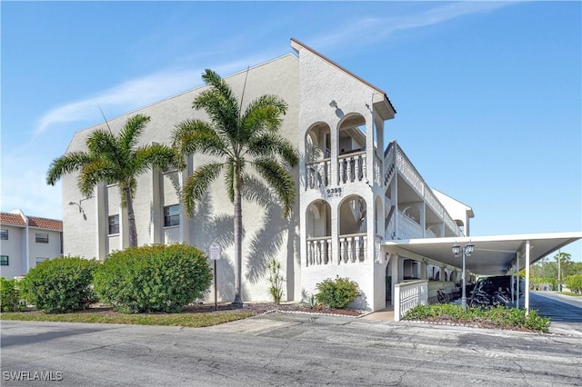 view of front facade with a balcony, an attached carport, and stucco siding