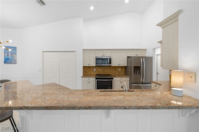 7735 Citrus Hill Ln, Naples, FL 34109 - kitchen with stainless steel appliances, high vaulted ceiling, a sink, a kitchen bar, and a peninsula
