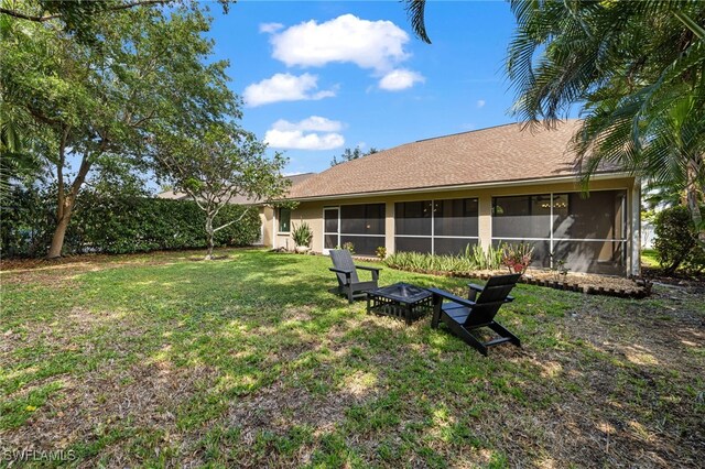 7735 Citrus Hill Ln, Naples, FL 34109 - rear view of house featuring a sunroom, a lawn, and an outdoor fire pit
