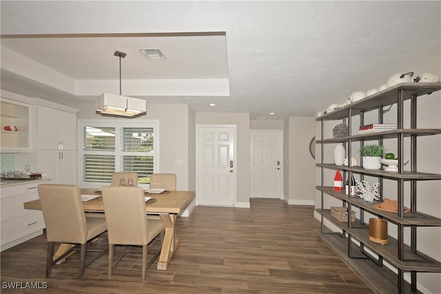 dining room with dark wood-style flooring, recessed lighting, a raised ceiling, visible vents, and baseboards