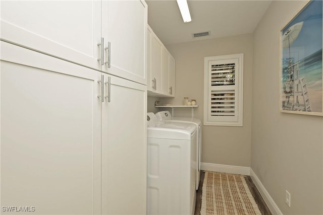 clothes washing area featuring visible vents, separate washer and dryer, cabinet space, and baseboards