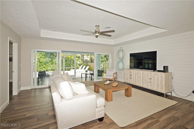 living room with a raised ceiling, a healthy amount of sunlight, and wood finished floors