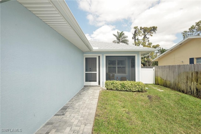 entrance to property featuring a yard, fence, and stucco siding