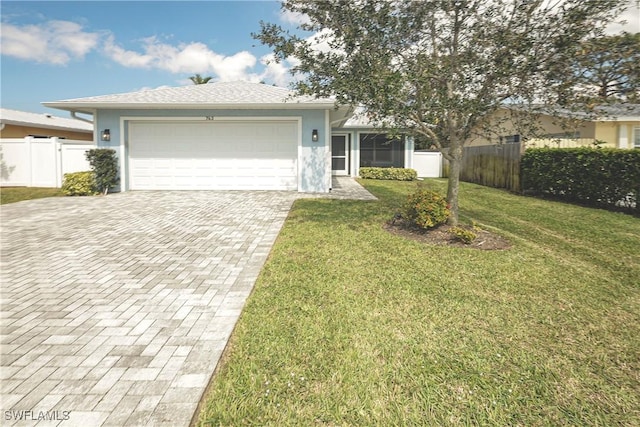 ranch-style home featuring a garage, decorative driveway, a front yard, and fence