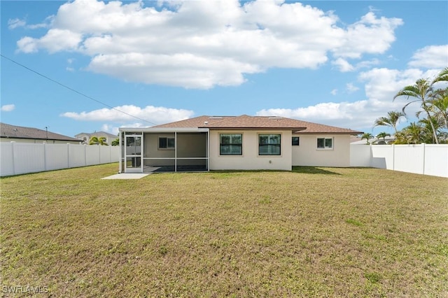 rear view of house featuring a sunroom, a fenced backyard, a yard, and stucco siding