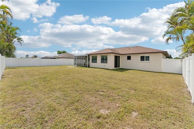 rear view of property featuring a fenced backyard, a yard, and stucco siding