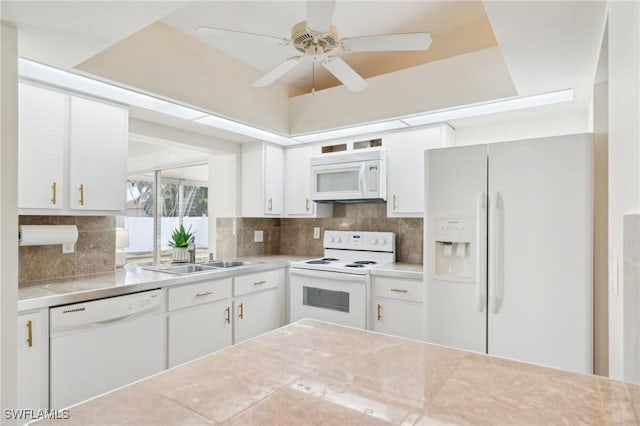 kitchen with a sink, white appliances, light countertops, and backsplash