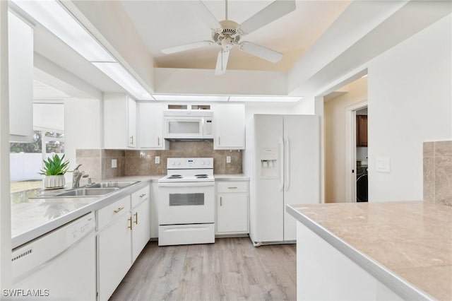 kitchen featuring white appliances, decorative backsplash, light countertops, white cabinetry, and a sink