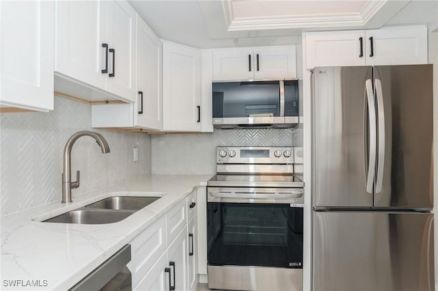 kitchen with stainless steel appliances, ornamental molding, white cabinets, a sink, and light stone countertops