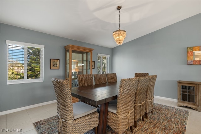 dining space with light tile patterned floors, baseboards, vaulted ceiling, and an inviting chandelier