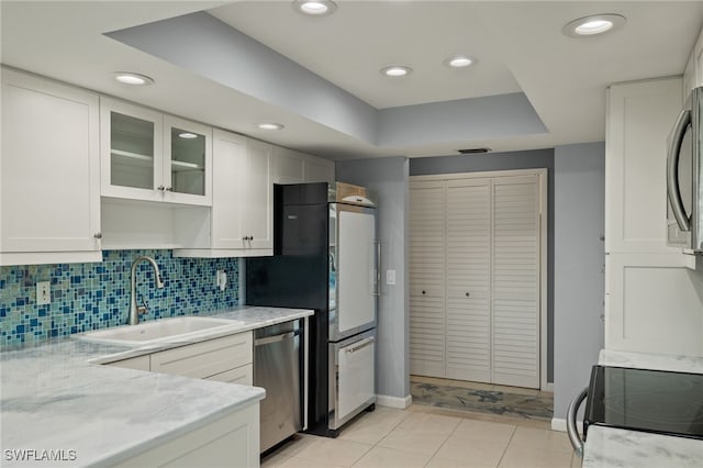 kitchen featuring appliances with stainless steel finishes, glass insert cabinets, white cabinets, and a sink