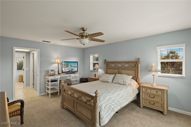 bedroom with light carpet, ceiling fan, visible vents, and baseboards