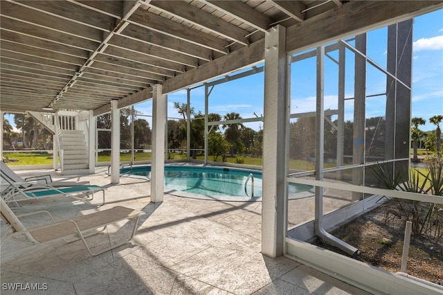 outdoor pool with glass enclosure, a patio area, and stairway