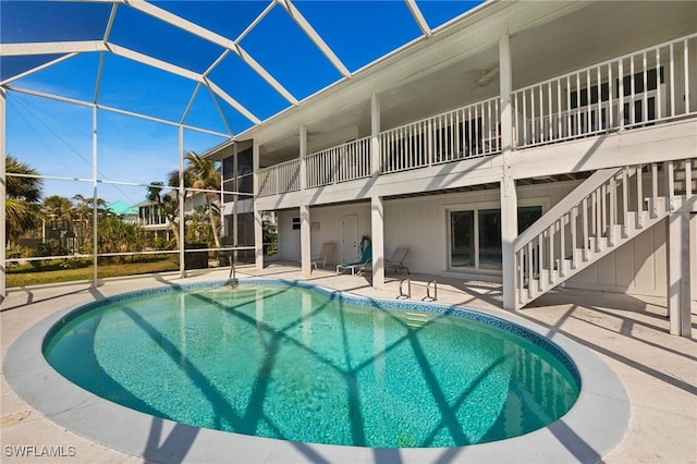 pool with stairs, glass enclosure, a patio, and a ceiling fan