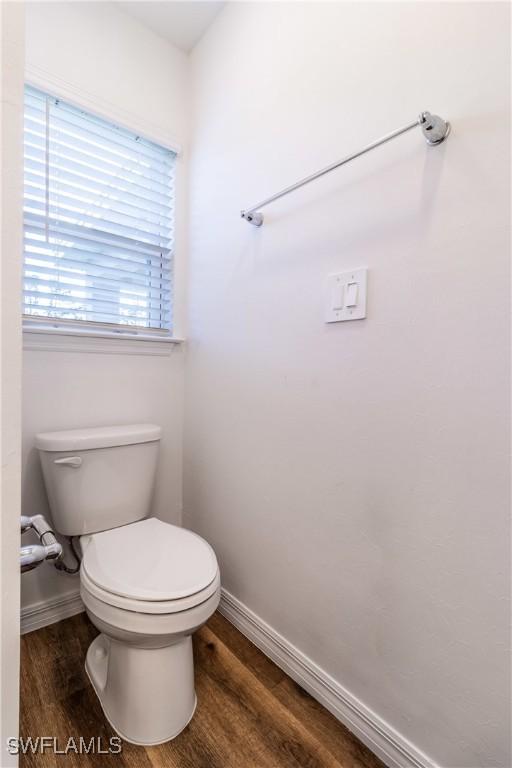 bathroom with toilet, baseboards, and wood finished floors