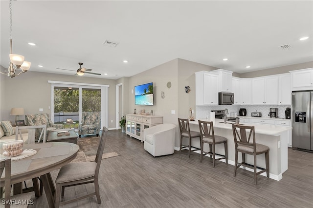 kitchen featuring stainless steel appliances, visible vents, open floor plan, light countertops, and tasteful backsplash