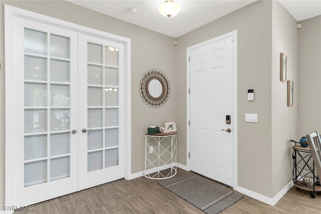 entryway featuring french doors, wood finished floors, and baseboards