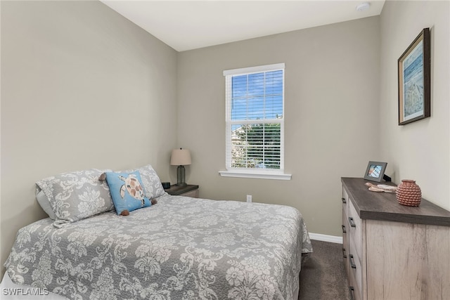 bedroom with dark colored carpet and baseboards