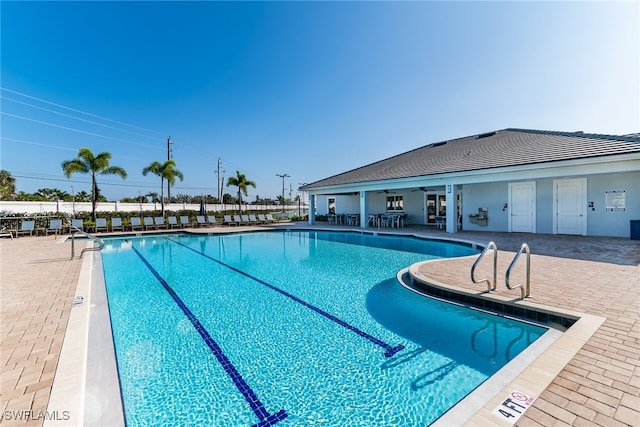 community pool with a patio area, fence, and a ceiling fan