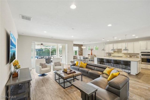 living room with light wood-style flooring, visible vents, and recessed lighting