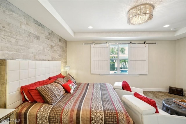 bedroom with recessed lighting, a barn door, baseboards, and wood finished floors