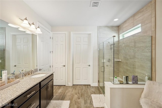 bathroom with baseboards, visible vents, wood finished floors, vanity, and a shower stall
