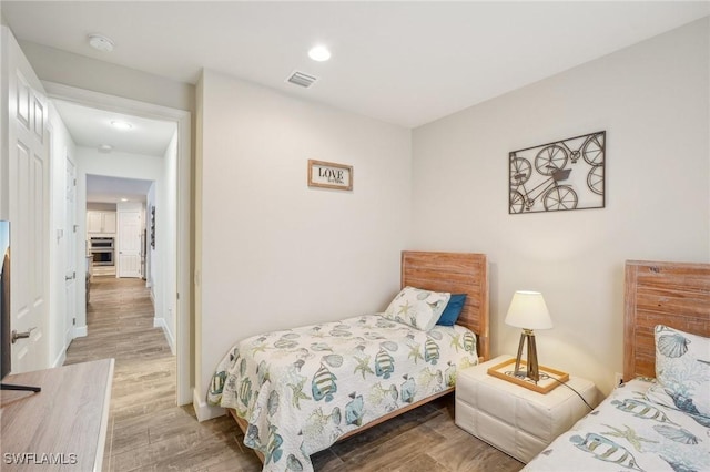 bedroom with baseboards, visible vents, and wood finished floors