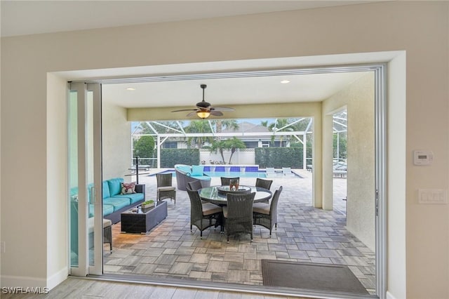 interior space with ceiling fan, outdoor lounge area, a lanai, and a fenced in pool