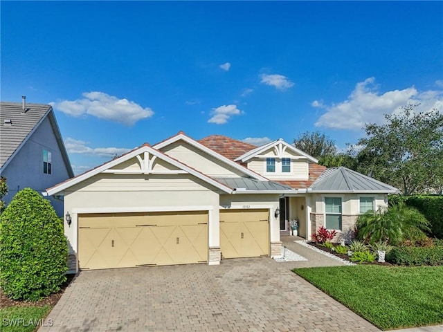 view of front of house with metal roof, a garage, decorative driveway, stucco siding, and a standing seam roof