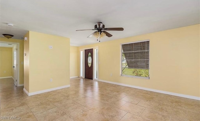 spare room featuring light tile patterned floors, ceiling fan, and baseboards