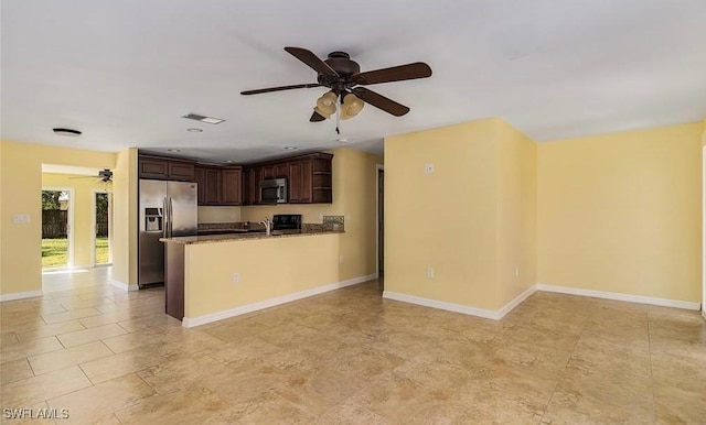 kitchen with dark brown cabinetry, stainless steel appliances, a peninsula, a ceiling fan, and baseboards