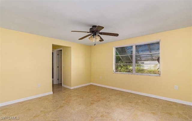 empty room featuring ceiling fan and baseboards