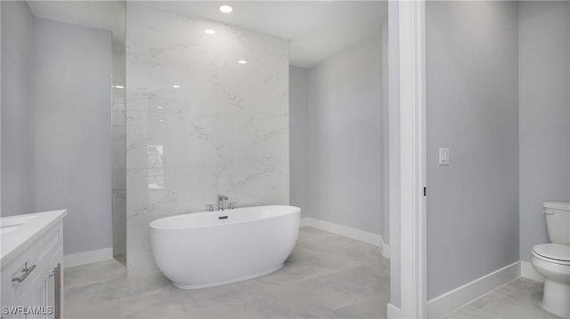 bathroom featuring marble finish floor, a freestanding bath, toilet, vanity, and baseboards