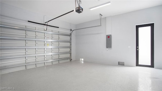 garage with a garage door opener, electric panel, and visible vents