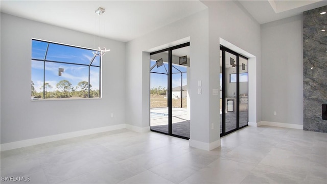 interior space with baseboards, a notable chandelier, and a high end fireplace