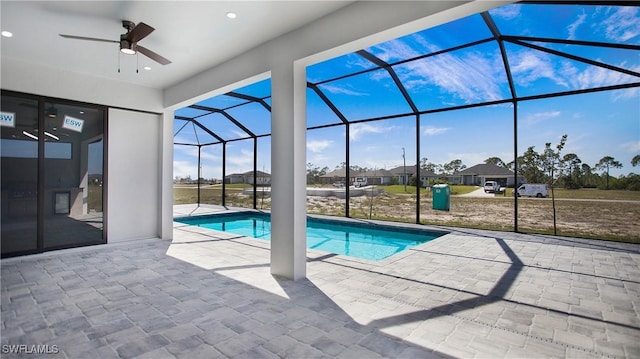 outdoor pool with ceiling fan, glass enclosure, and a patio area