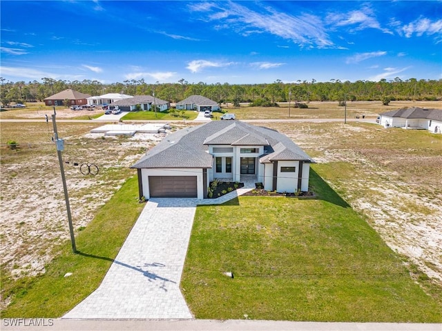 view of front of house with a front lawn, decorative driveway, and an attached garage