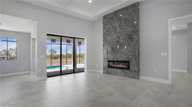 unfurnished living room with a high ceiling, baseboards, and a wealth of natural light