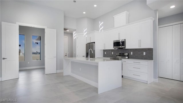 kitchen featuring a center island with sink, white cabinetry, and stainless steel appliances