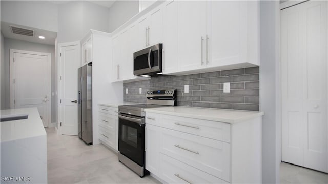 kitchen with stainless steel appliances, visible vents, white cabinets, light countertops, and backsplash