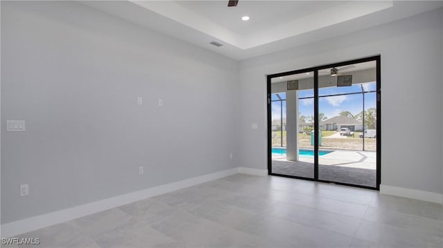 spare room with ceiling fan, a raised ceiling, visible vents, and baseboards