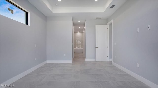 unfurnished room with a raised ceiling, visible vents, and baseboards