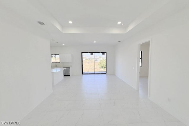 spare room with a tray ceiling, visible vents, and recessed lighting