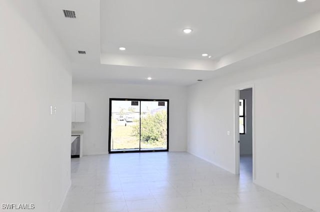 empty room with baseboards, a tray ceiling, visible vents, and recessed lighting